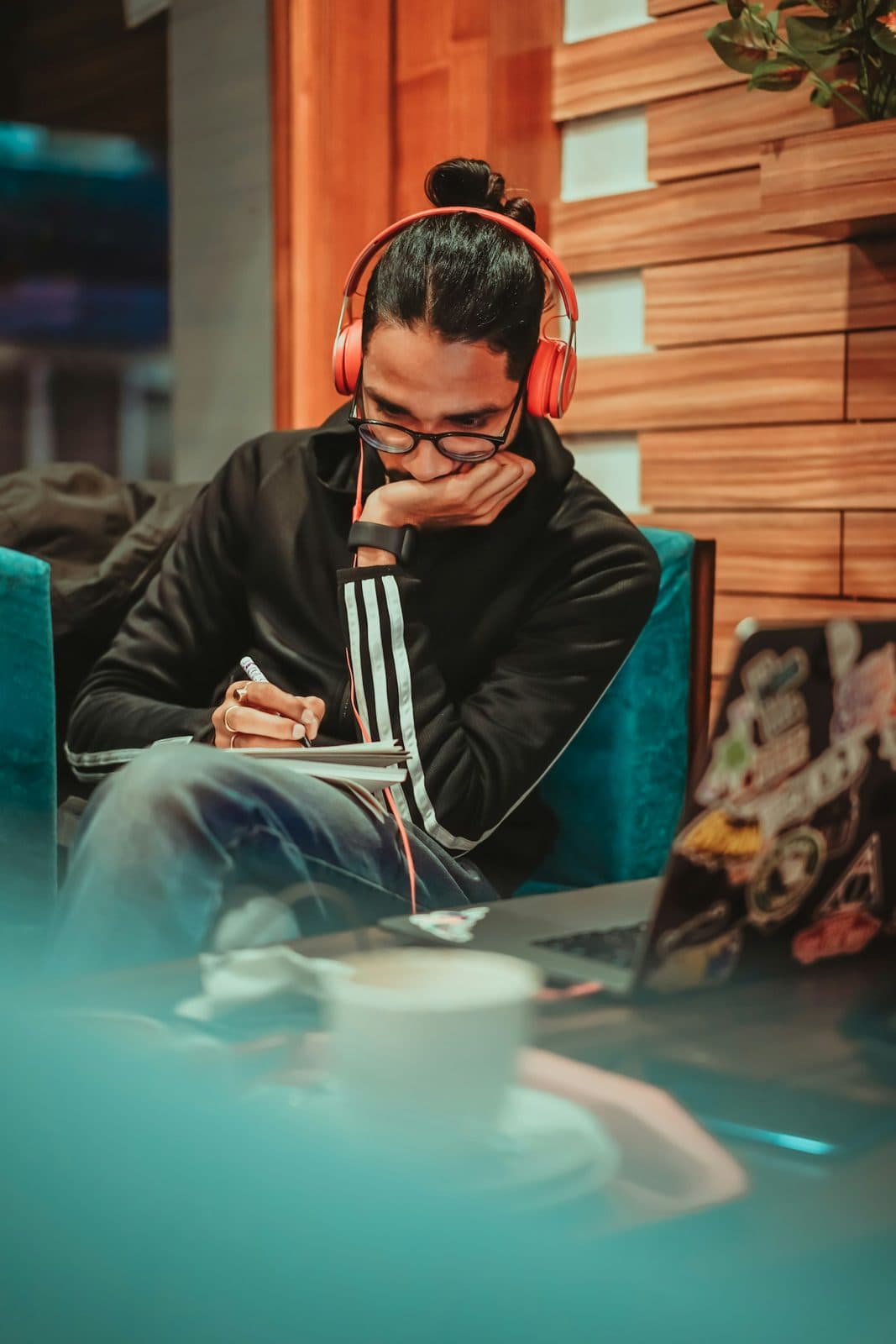 Persona con audífonos escribiendo en un cuaderno en una cafetería