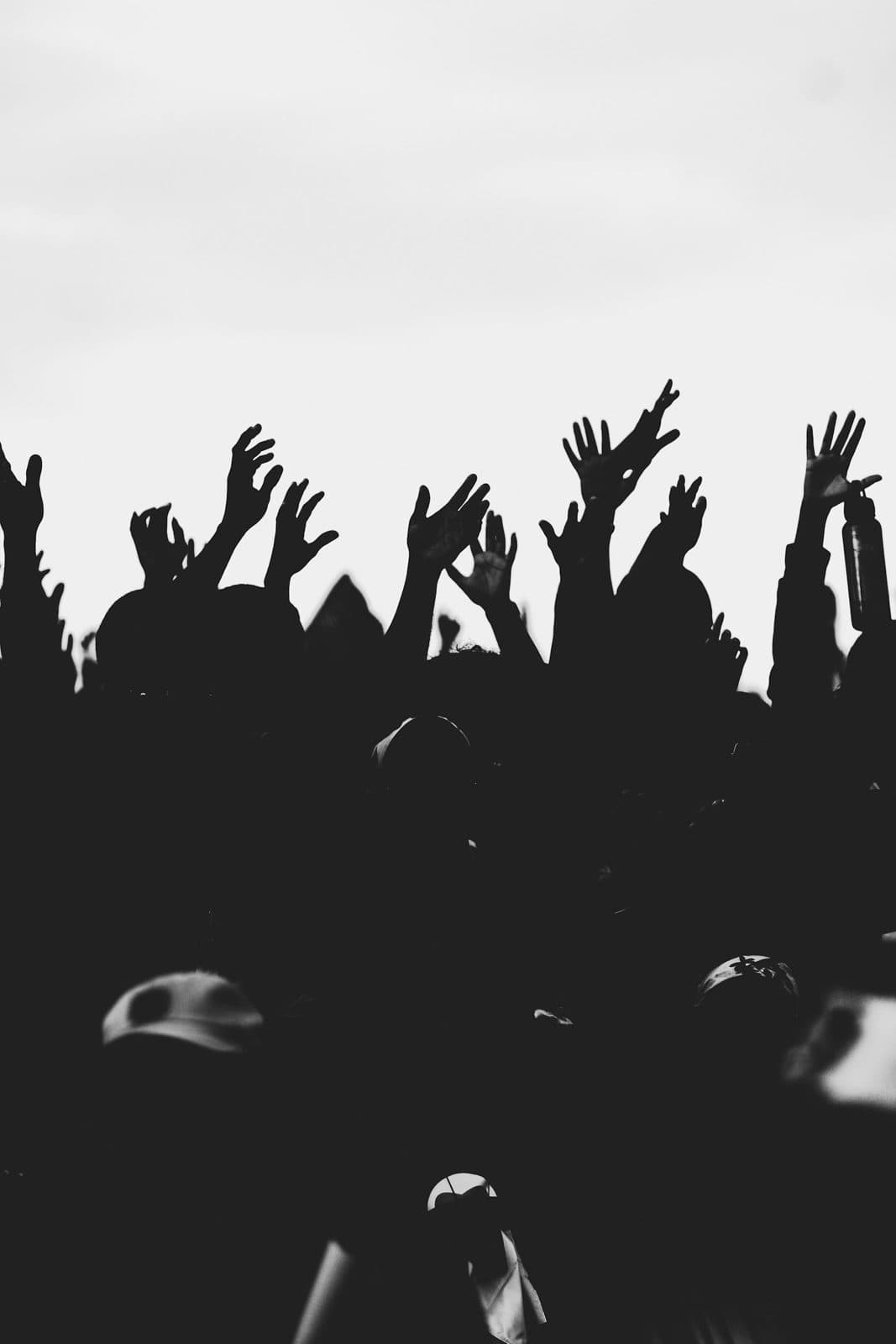 Siluetas de una multitud con las manos levantadas en un festival de música
