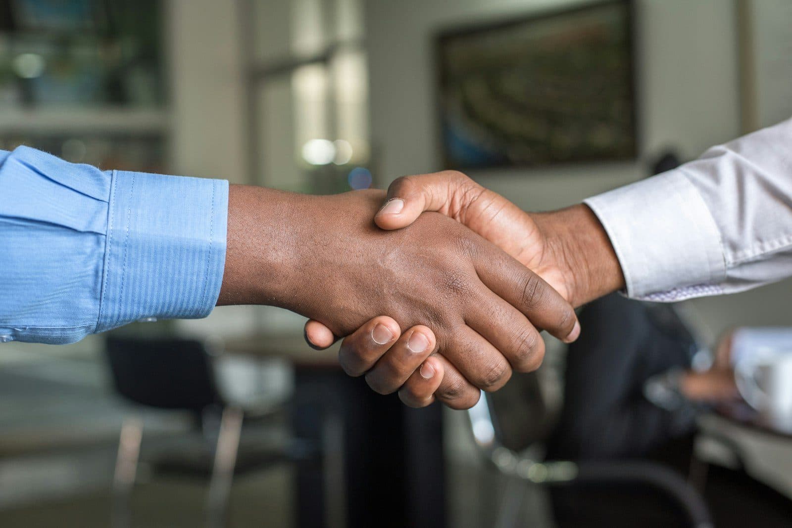 Dos personas dándose la mano en una oficina, cerrando un acuerdo