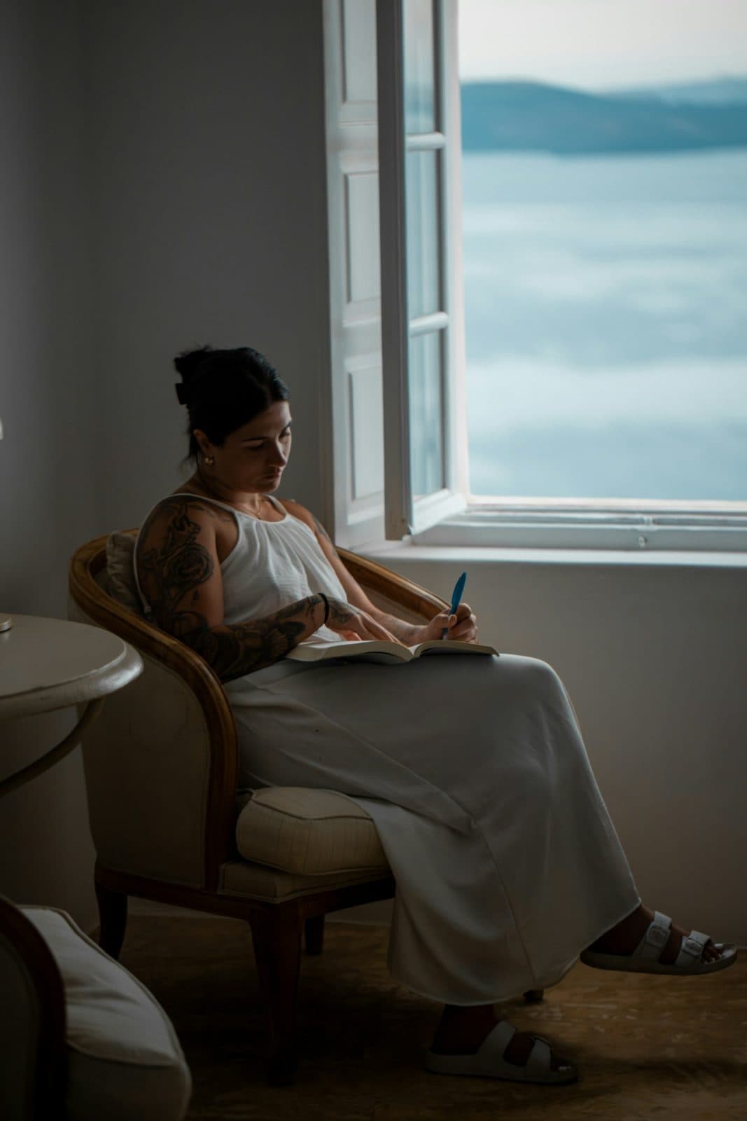 Mujer escribiendo en un cuaderno junto a una ventana, en un momento de reflexión tranquila